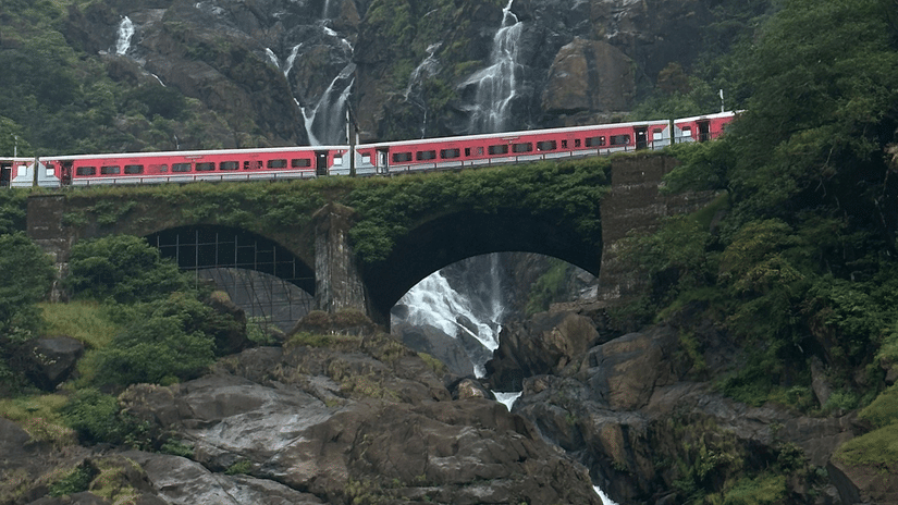 Dudhsagar Waterfalls with a train crossing the iconic railway bridge.