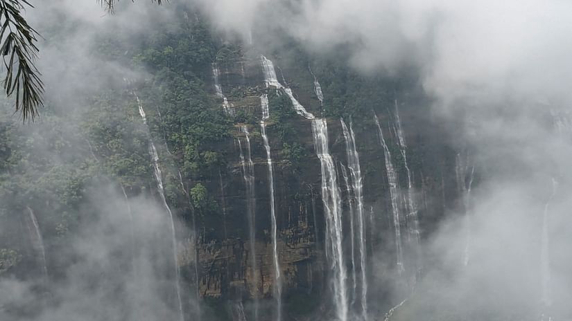 A waterfall in the middle of a forest at the Seven Sisters Fall in Cherrapunji.