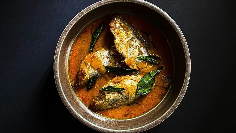 An aerial view of a fish curry inside a bowl that is placed on a table