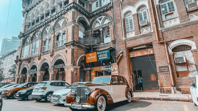 A view of Colaba Causeway with a vintage car parked in front of a building.