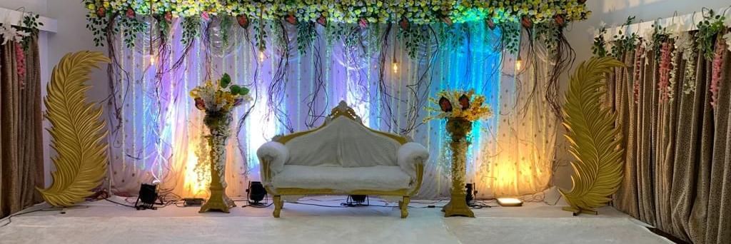 Floral stage setup with soft lighting and golden curtains, ideal for weddings and special events at Mayur Retreat.