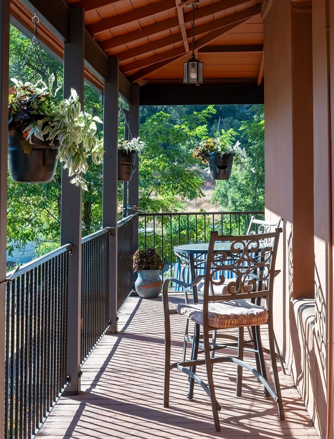 Balcony seating area with wooden roof and chairs overlooking greenery at The Groveland Hotel.