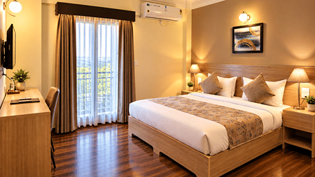 Premium Studio at Starlit Suites, Shirdi, with a bed, patterned runner, wooden flooring, work desk, wall mounted television and curtained balcony door.