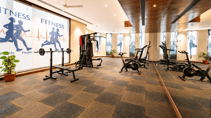 Fitness centre with a row of exercise machines and fitness themed wall art at Eastlynn Resort, Rishikesh.