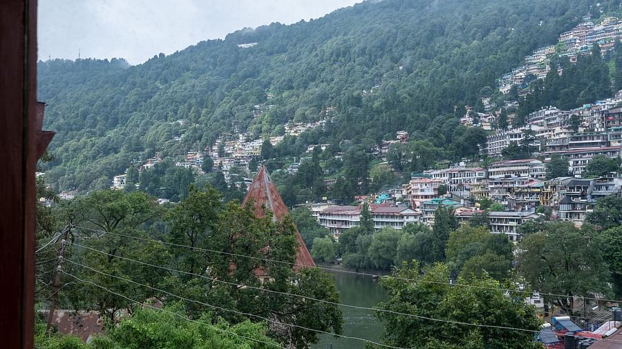 Valley perspective from Himalaya Hotel, Nainital showing densely built hillside town, traditional rooftops, and forested mountains shrouded in morning mist.