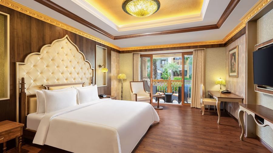 A hotel room in Mahabalipuram with rich wooden flooring, a large bed, and comfortable seating arrangement – Kaldan Samudra, one of the finest Mahabalipuram beach resorts