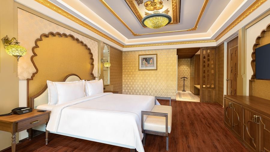 A spacious bedroom with clean white linen and ornate gold frames above the beds – Kaldan Samudra, one of the best luxury hotels in Mahabalipuram