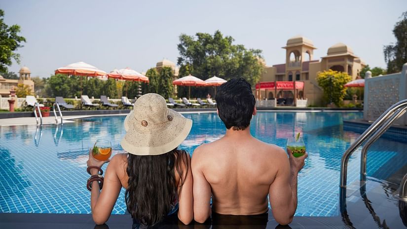 A couple unwinding in the pool, savoring drinks at HERITAGE VILLAGE RESORTS & SPA, MANESAR.