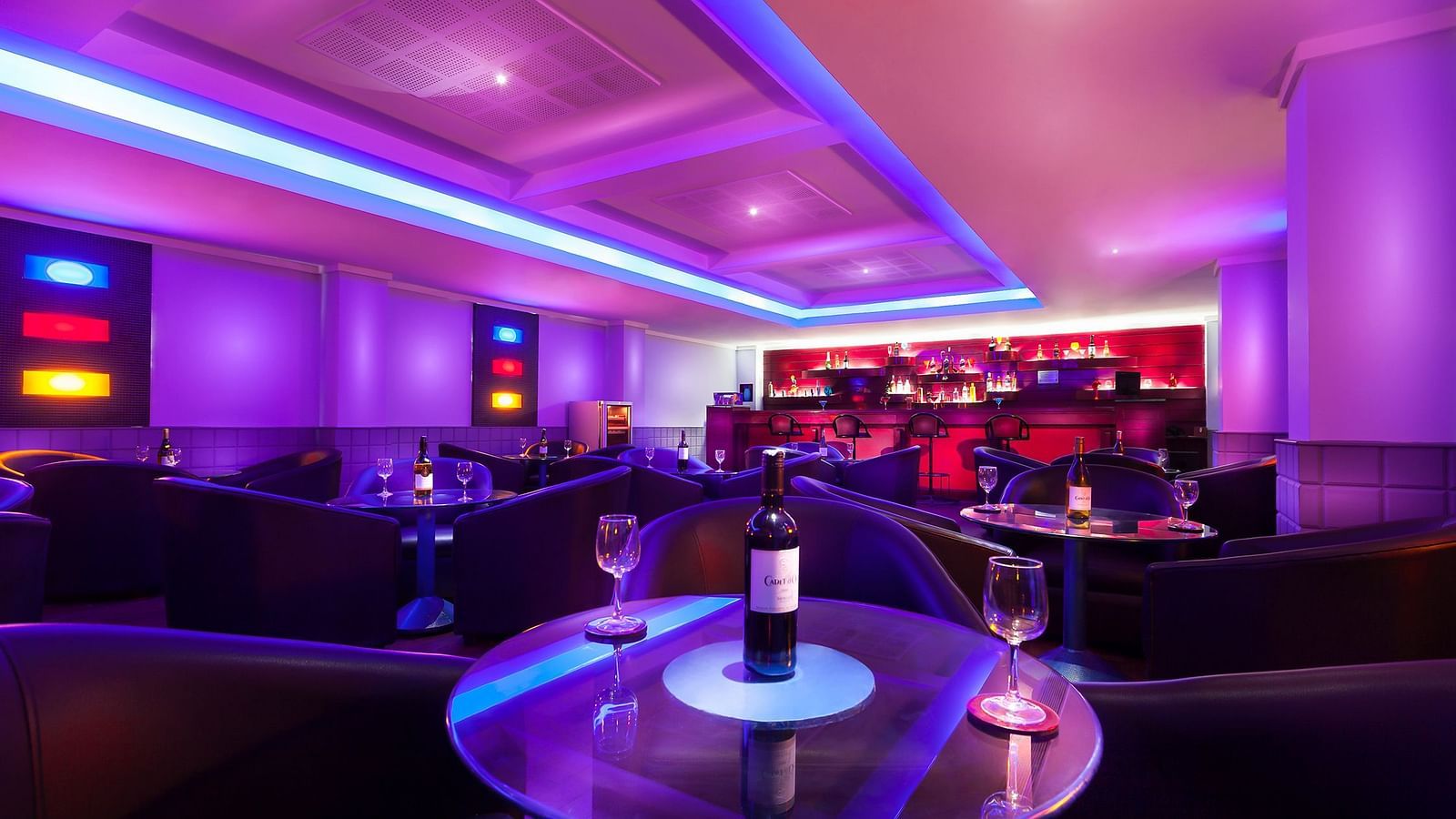 An image of a bar with illuminated purple lights at Regency Madurai by GRT Hotels