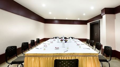 A view of the conference hall with a white table surrounded by chairs at Regency Tuticorin by GRT Hotels.