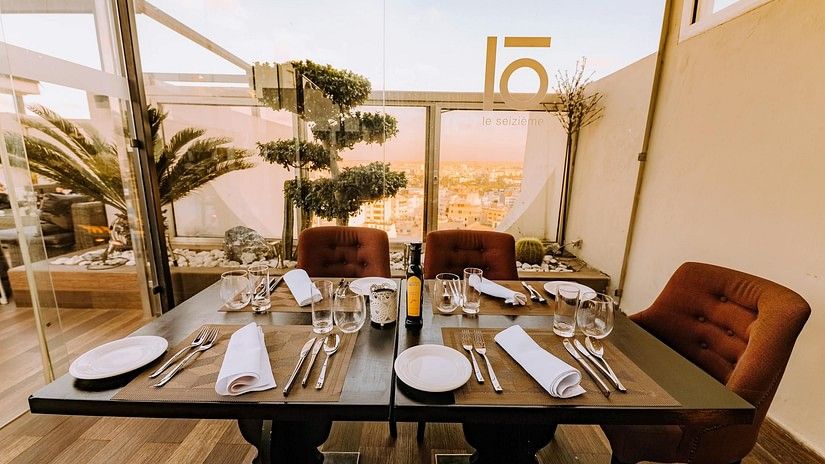 An outdoor dining area with a decorated table, overlooking a cityscape.