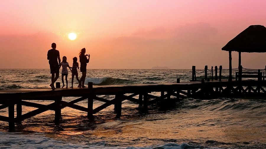 A family on a dock at sunset by the sea.
