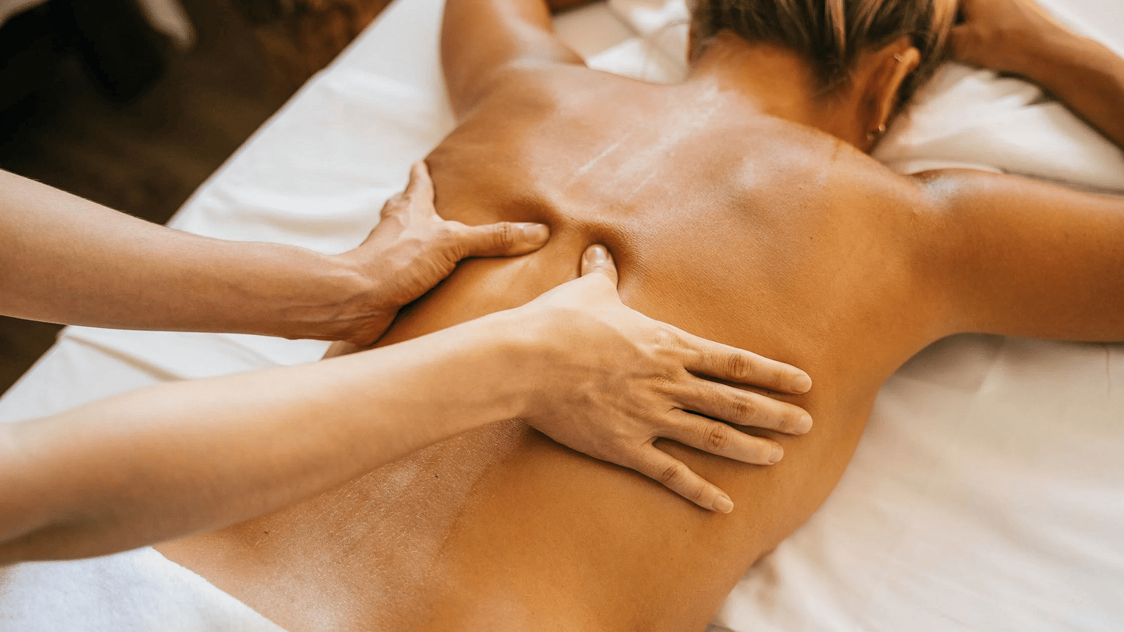 An image where the massage therapist is massaging the back of a woman in a spa.