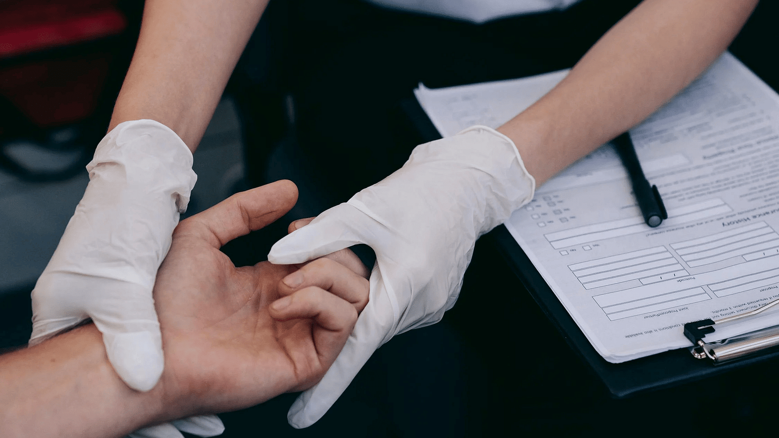 A doctor holding the hand of a person and checking the pulse.