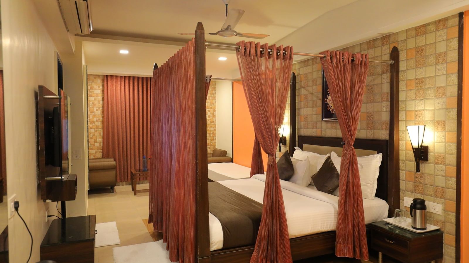 A wide view of a Krushnai Resort bedroom with a four-poster bed, dark wood furniture, and warm lighting.