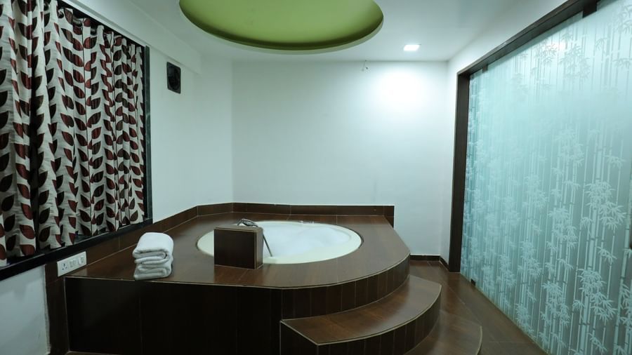 A washroom in Krushnai Resort room featuring a large, built-in Jacuzzi tub with steps.