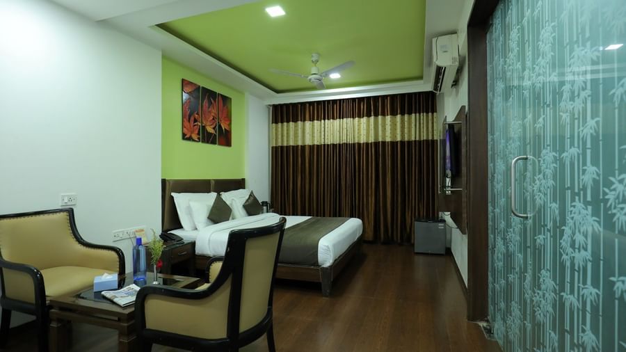 A spacious bedroom at Krushnai Resort with a bed, a large wall-mounted TV, and a seating area for guests.