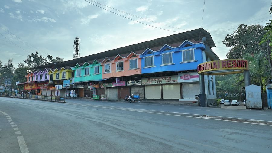 The Krushnai Resort sign marks a long building with colourful facade lining a quiet road under a cloudy sky.