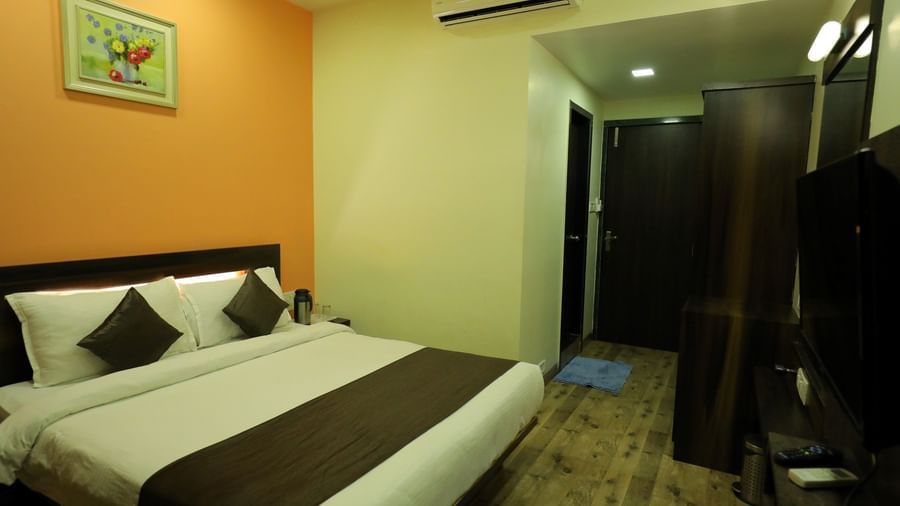 Executive Room with wooden flooring in Krushnai Resort, featuring a king size bed with brown runner, air-conditioner and a wardrobe.