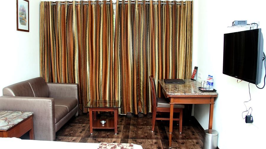 Hotel room with seating area, desk, and wall-mounted TV