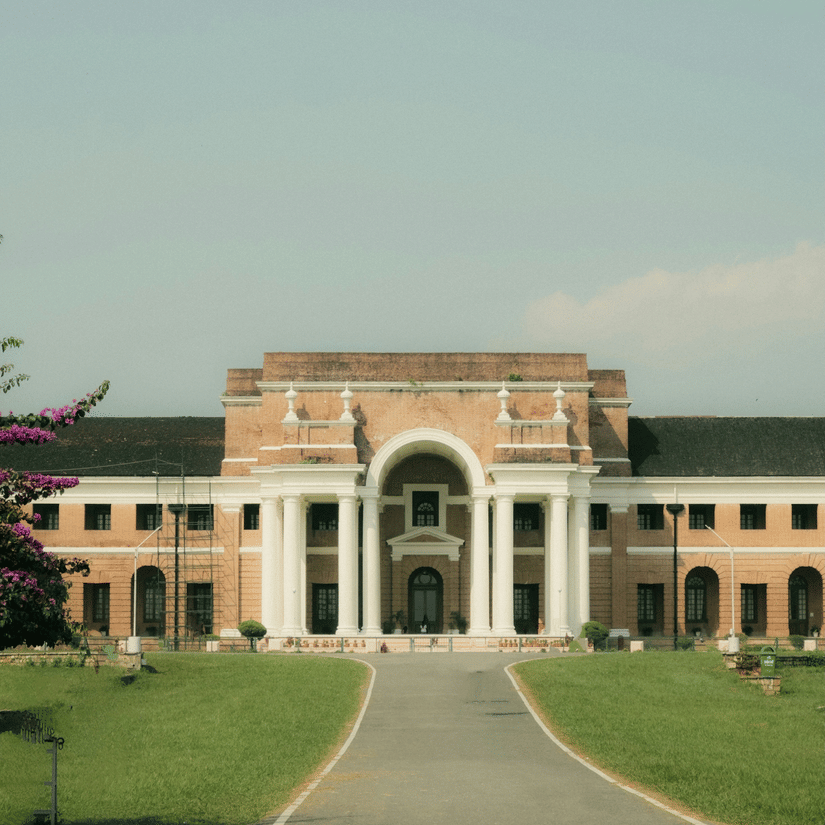 Facade of the Forest Research Institute, one of the top tourist places in Dehradun, Uttarakhand, with manicured lawns in between a pathway leading to the entrance.