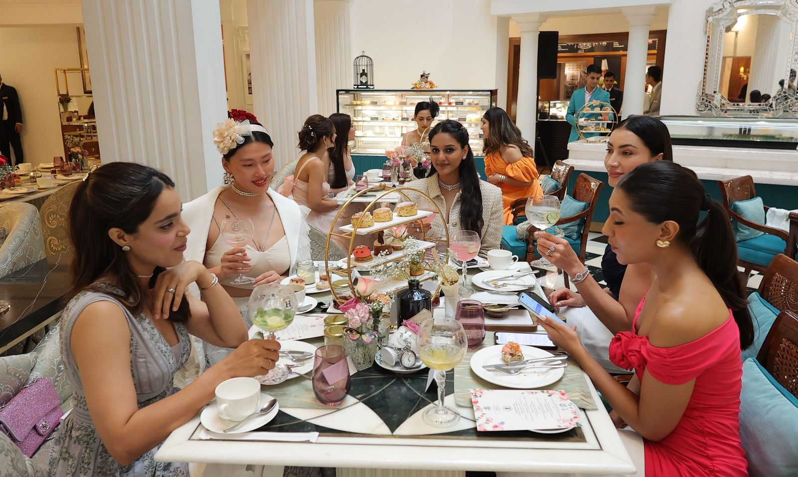 People enjoying their Buffet High Tea with an elegant setup featuring pastries and scones at The Claridges, New Delhi