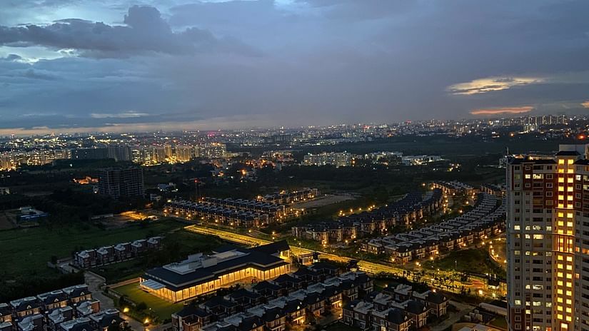 Aerial view of illuminated Bengaluru cityscape at dusk, showcasing urban skyline and infrastructure.