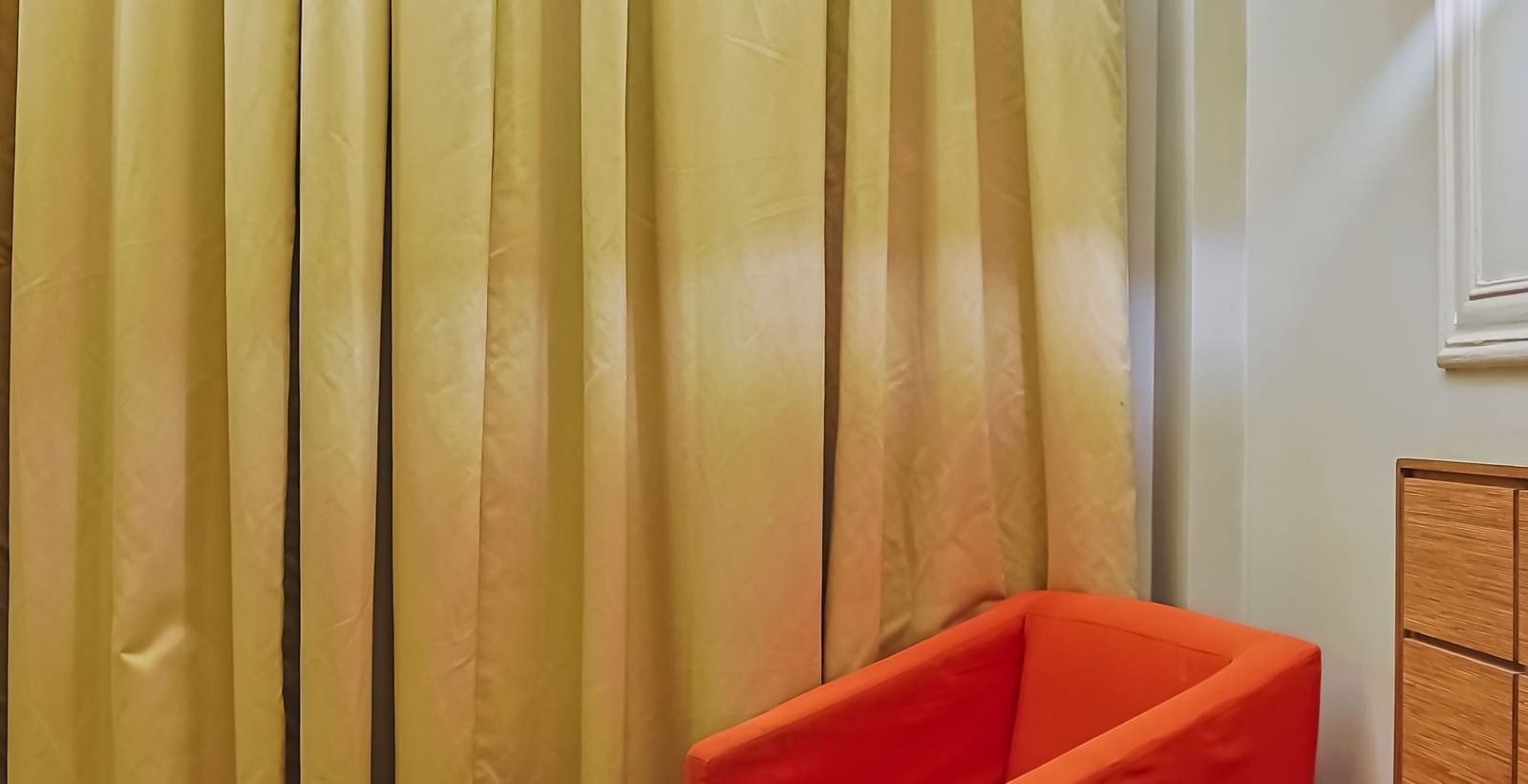 Seating corner with orange chair, round table and curtains at Max Hotel Prayagraj.