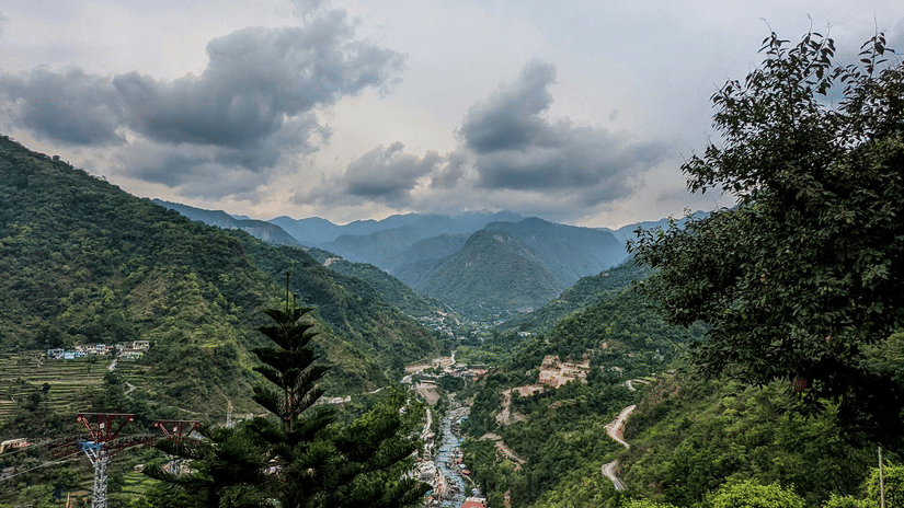 Mountain landscape in Dehradun, the best hill station for summer, with cloudy sky, hills, distant valleys, and a viewpoint railing overlooking a scenic natural area setting