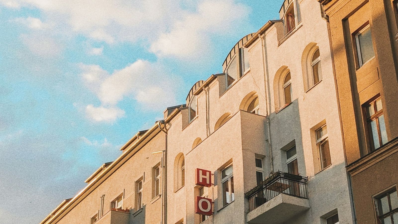  A low-angle view of a row of European-style buildings with balconies under a blue sky