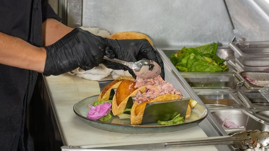 Chef plating a colorful gourmet dish with care in the prep area at Narrow Gauge Inn.