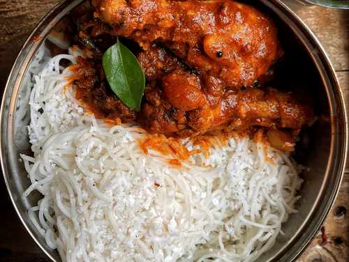 A plate of idiyappam and chicken curry.