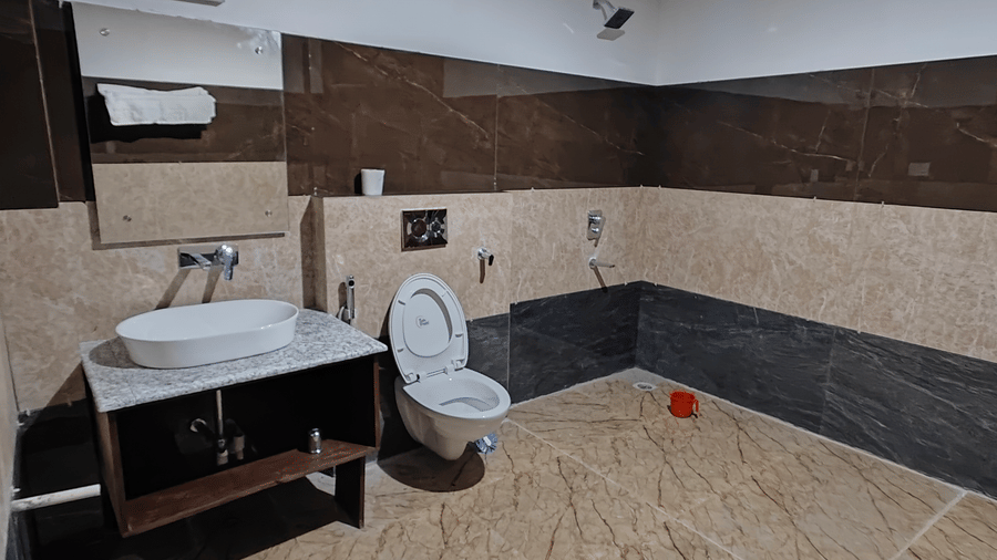 A clean and modern bathroom featuring dark and light brown tiling with a white porcelain vanity at Indus Serenity Retreat.