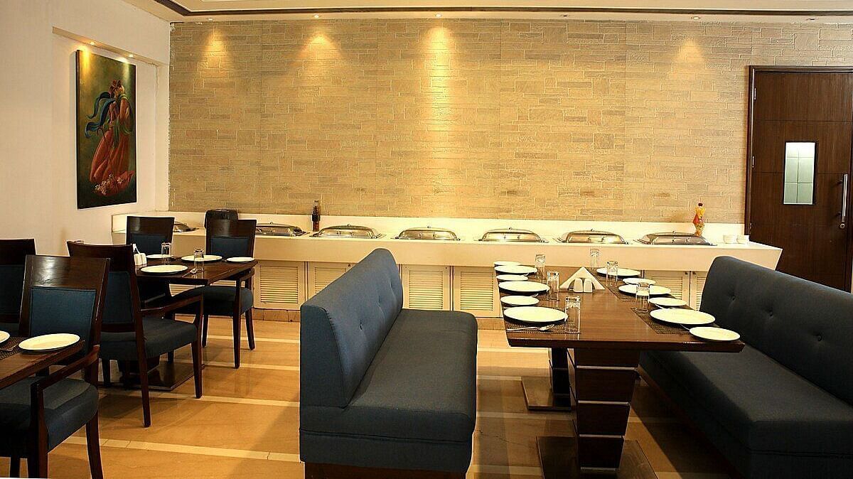 Tables and chairs neatly arranged with cutlery set on the table at Café Inde, Inde Signature Tower, Gurgaon