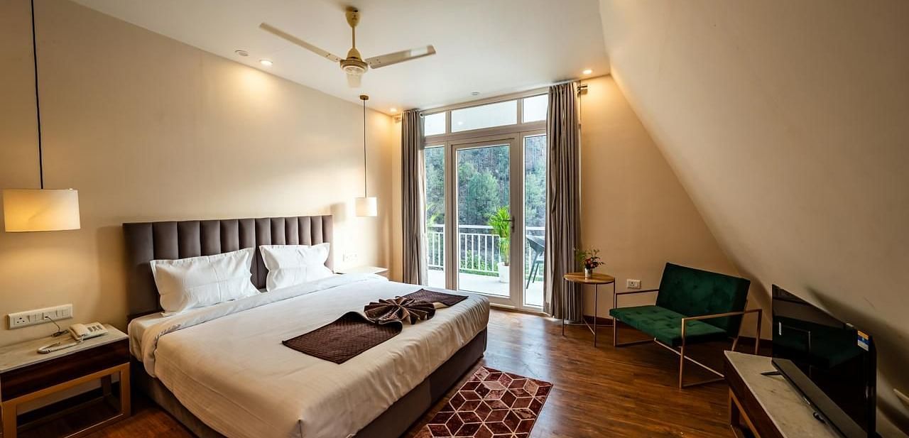 A hotel room showing a bed, a TV, and a door to the balcony.