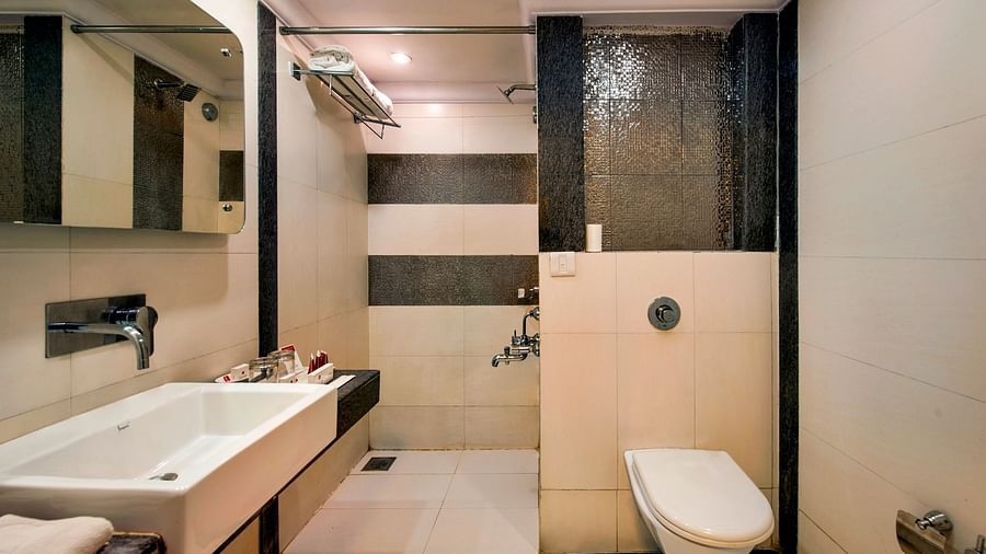 Bathroom with a white bathtub, a toilet, a sink, and a glass-enclosed shower, clean and modern - Lords Inn Vadodara