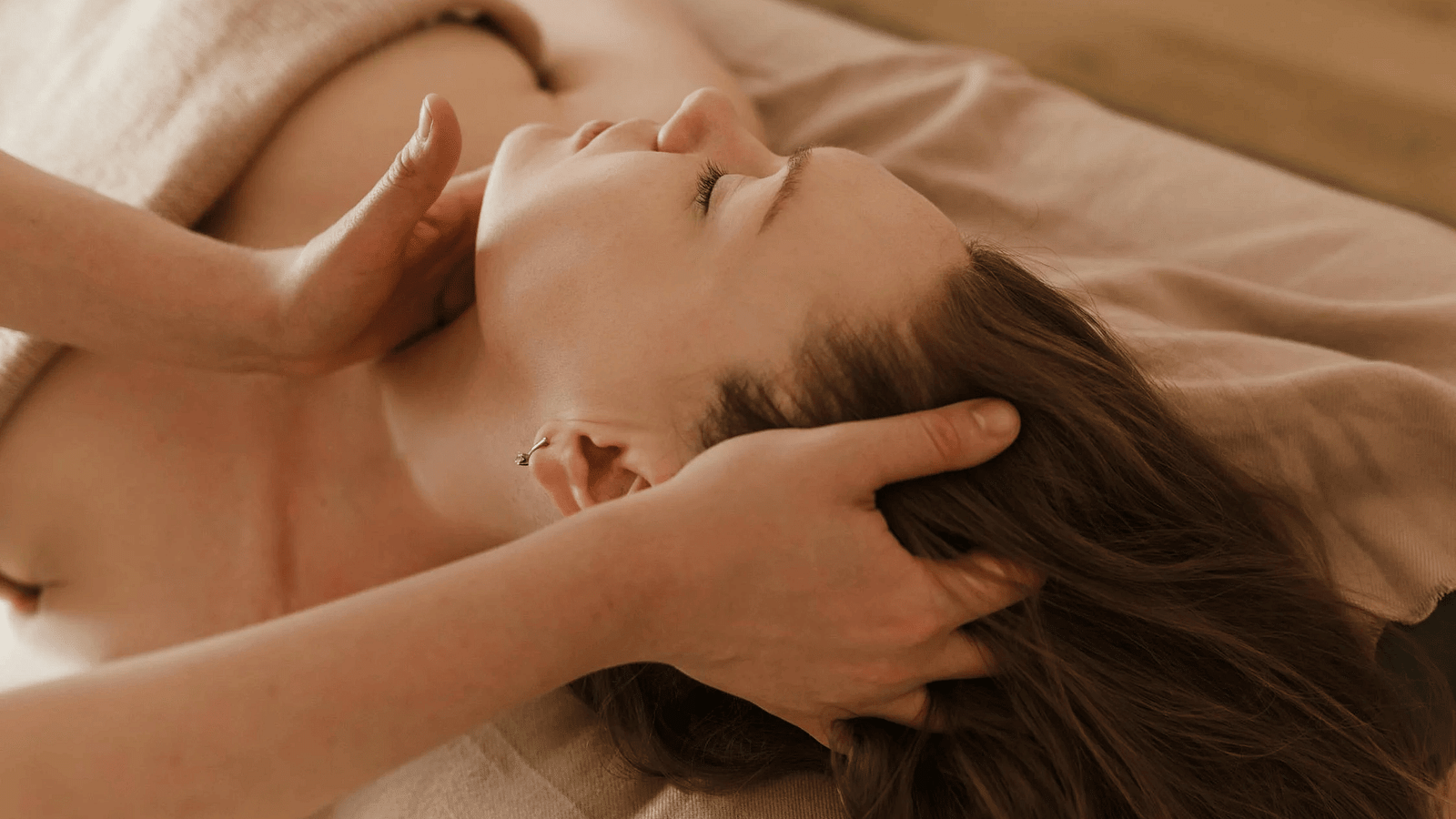 An image where the neck of a woman is getting massaged in a spa like setting.