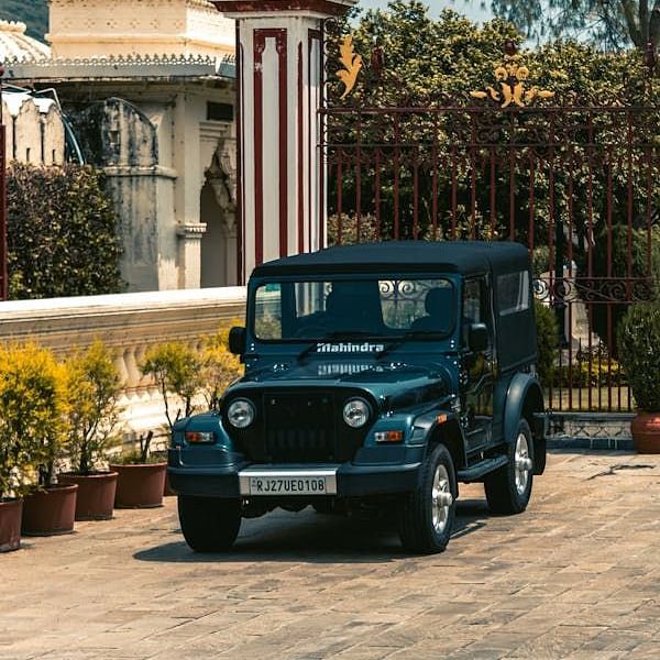 A parked Mahindra Thar with potted plants are placed near the walls as decoration during daytime