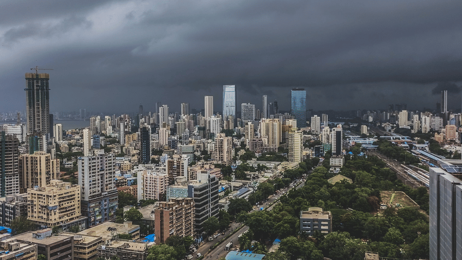 Dark storm clouds gather over a sprawling modern city with tall skyscrapers and green parks below.