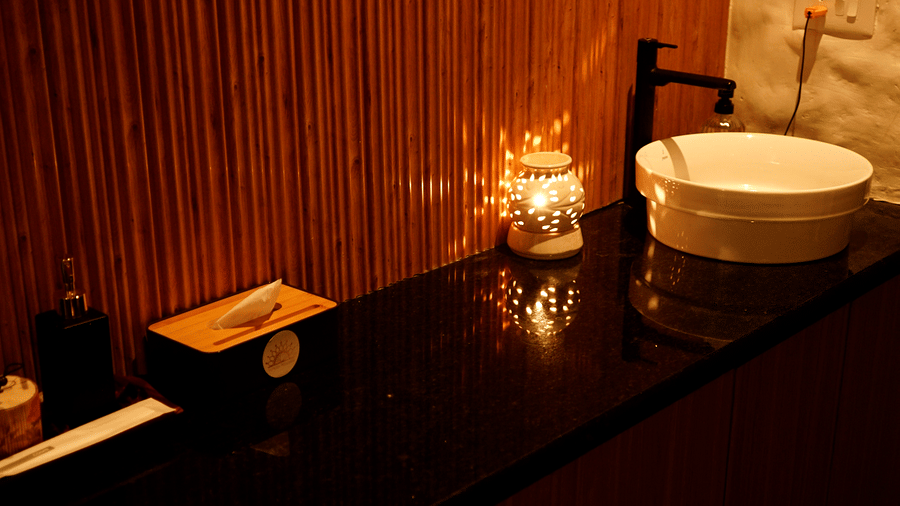 A modern spa treatment room with dark wood cabinets, a white bowl sink, and warm, atmospheric lighting at Hotel Hukam's Lalit Mahal.