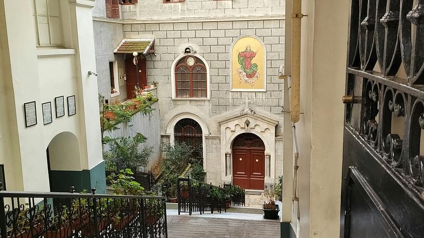 A view through an arched entryway or corridor inside an old building, showing a staircase and architectural details.
