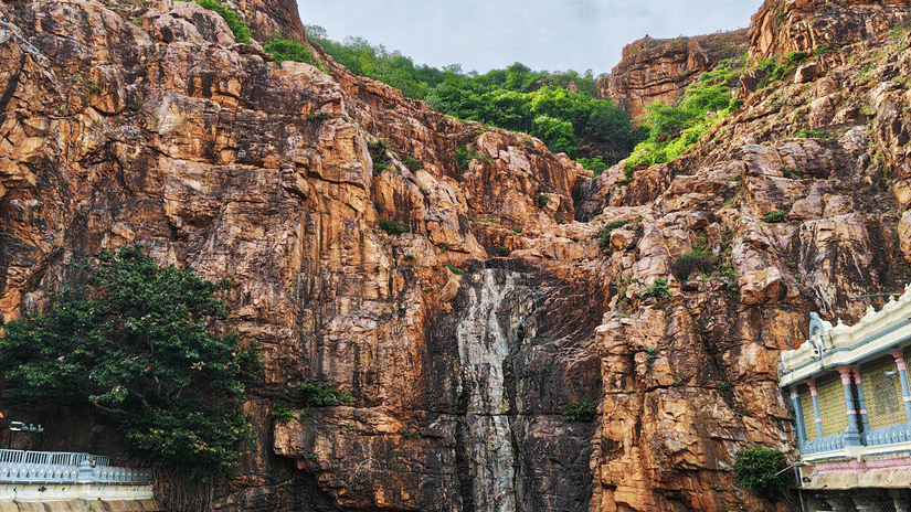 A colossal stone statue carved into a cliff face overlooking a green pool.
