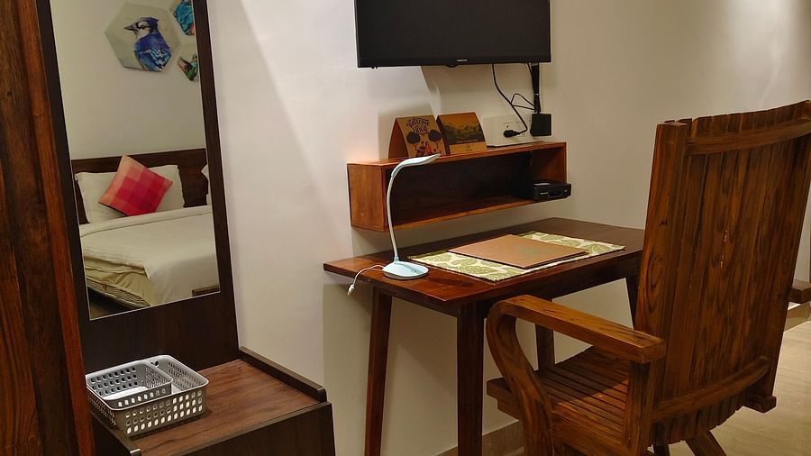 Image of a chair and a study table with a television on the top of it and a small cupboard and a mirror in 101 non-ac room at Ananda Holiday Home, Wayanad 7