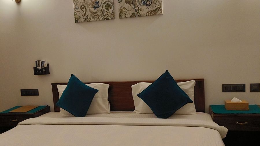 Front view of a double bed with blue pillows in 102 room at Ananda Holiday Home, Wayanad 7