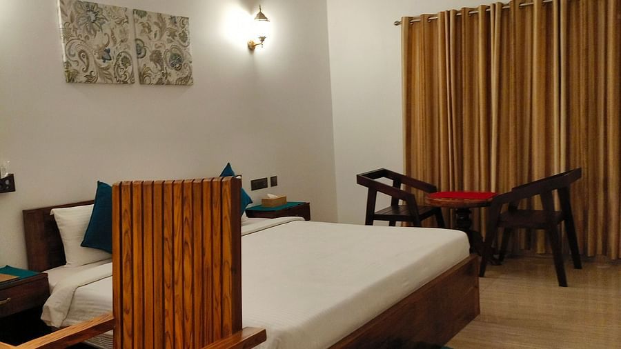 Side view of a chair with a desk and a double bed behind it in 102 room at Ananda Holiday Home, Wayanad 8
