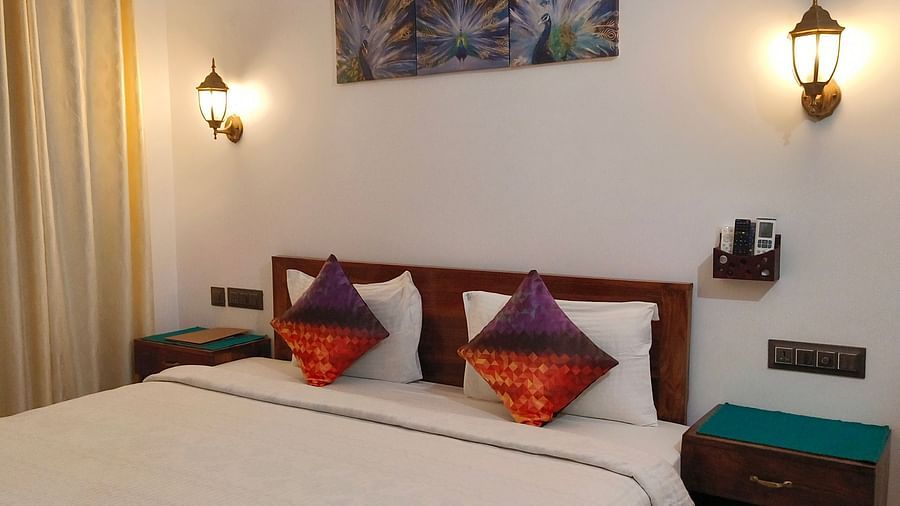 Another view of a double bed with two colourful pillows in 103 room at Ananda Holiday Home, Wayanad 3