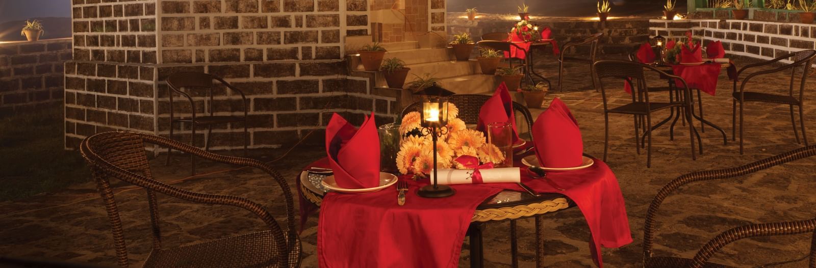 Outdoor dinner setup at night with red tablecloths at Polo Resort Cherrapunjee.