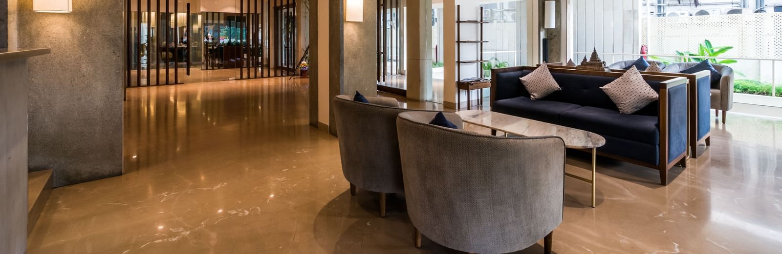 A stylish hotel lobby featuring comfortable grey sofas and warm lighting, perfect for relaxation at Shilton Dee Cee.
