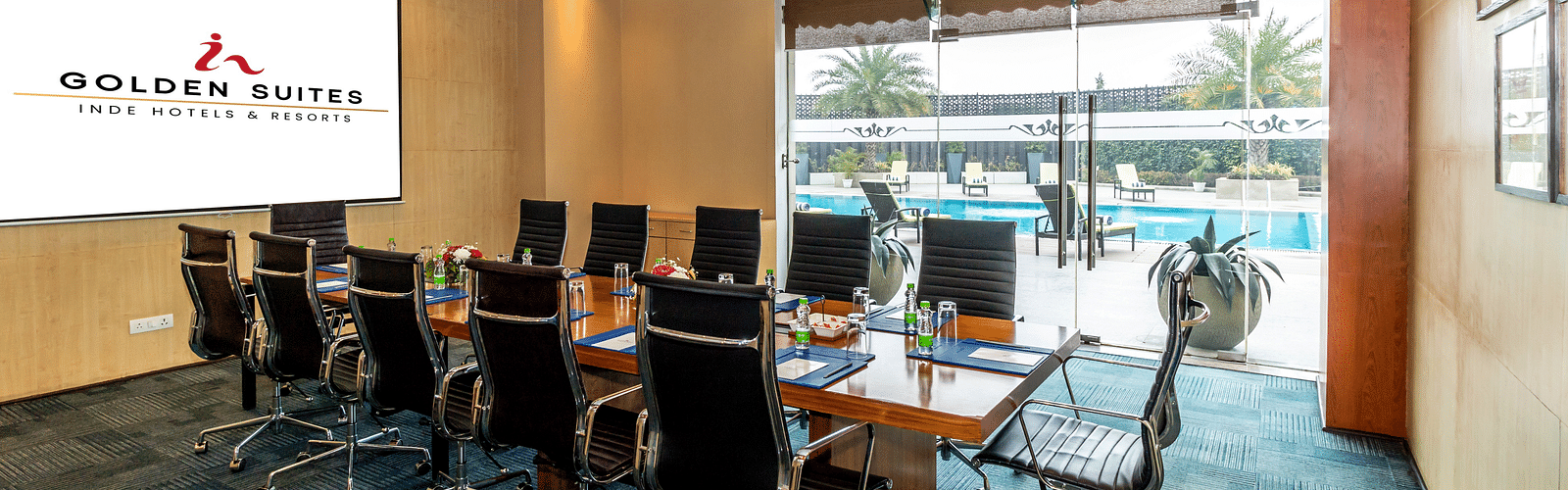 Boardroom with chairs round the table and a screen at Golden Suite