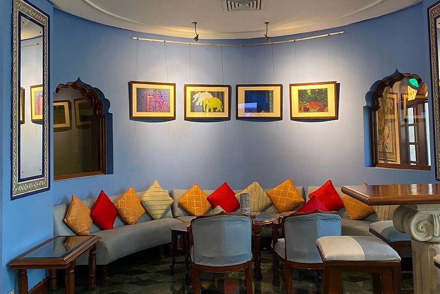 A calming blue wall with four framed paintings with seating for the guests at ta BLU Rooftop Bar at Clarks Amer, Jaipur
